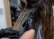 beautiful young brunette girl sitting on the procedure of hair coloring
